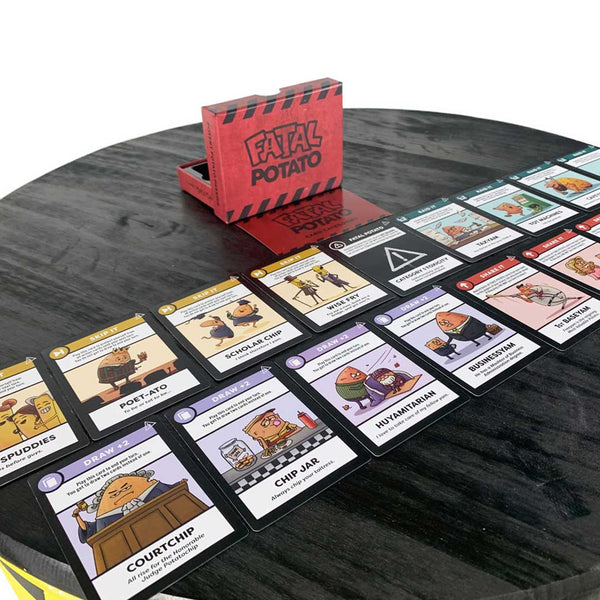 A side-angle view of the Fatal Potato expansion package with all of the included cards spread out in front of the box