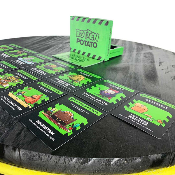 A side-angle view of the Rotten Potato expansion package with the included cards spread out in front of the box